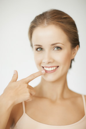 smiling lady pointing to her teeth after teeth whitening procedure